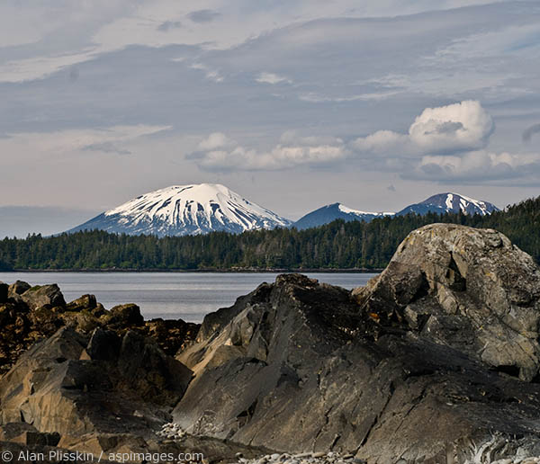 The shoreline rocks accentuate the shape of the mountains across the bay from Sitka.