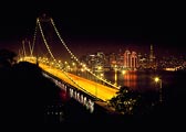 The lights of San Francisco glow across the Bay beyond the Oakland Bay Bridge.