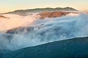 Early morning fog breaks up as the sun lights Mt Tamalpais and other ridges in the Marin Headlands.