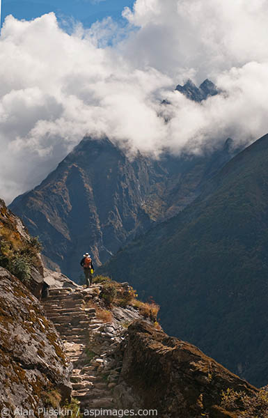 A distant mountain breaks through the clouds as this hiker reaches a crest in the trail.