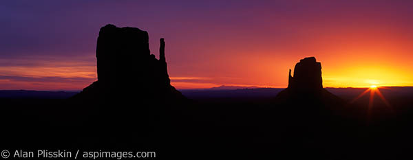 The Mittens at Monument Valley backlit at sundown.